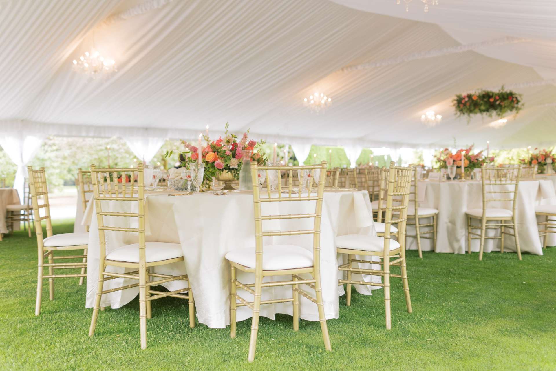 White wedding tent with gold Chiavari chairs and floral centerpieces, showcasing full-service Wedding Planner services.