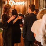 Vintage Christmas party at The Kelley Farm, guests socializing and enjoying cocktails with "Cheers" neon sign.